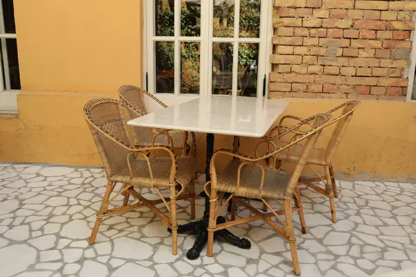 Table and chairs near wall with window, outdoors