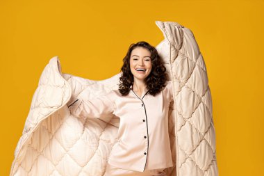 Kız sarı bir arka planda battaniyeye sarılmış..