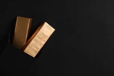 Siyah arkaplanda altın folyoyla çikolatalar, metin için boşluk