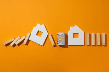 Evler, tahta bloklar ve turuncu arka planda nakit para, metin için alan