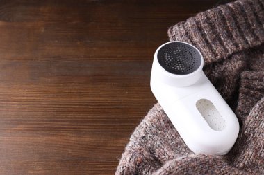 Elbiselerin üzerine kumaş traş makinesi, koyu bir arkaplan.