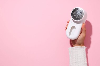 Pembe arka planda kumaşları traş eden bir makine..