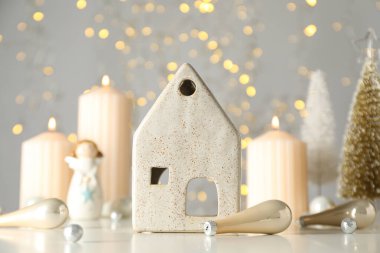 Mumlar, seramik ev ve ışık arka planında yeni yıl baloları