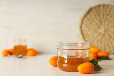 Kumquat, ışık arkaplanındaki kavanozlara sıkıştır, metin için boşluk