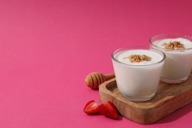 Ahşap zeminde yoğurtlu kaseler pembe arka planda duruyor, metin için yer var.