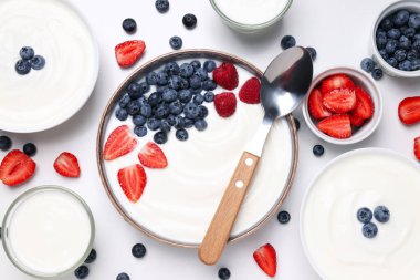 Yoğurt ve böğürtlenli kaseler, beyaz arka planda kaşık, üst manzara