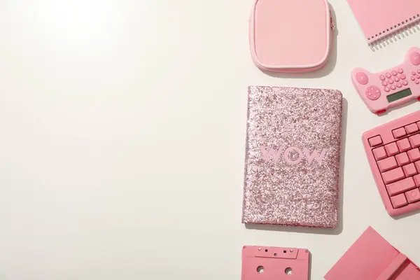 Pink notepads, joystick, cassette and keyboard on white background, space for text