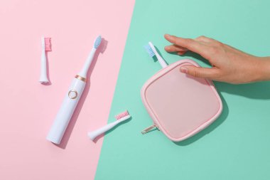 Elektrikli diş fırçaları, çanta ve el pembe ve yeşil arka plan, üst görünüm