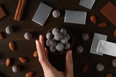 Çikolata topları, çikolatalar ve bademlerle ahşap bir kasede.
