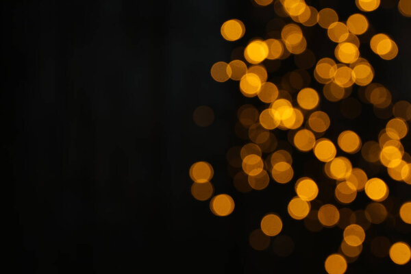 Yellow blurred lights on black background, space for text