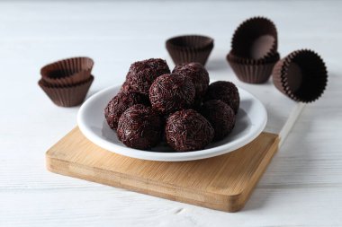 Brigadeiro beyaz arka planda mutfak tahtasının üzerinde kağıt ve tabak formlarıyla, kapatın.