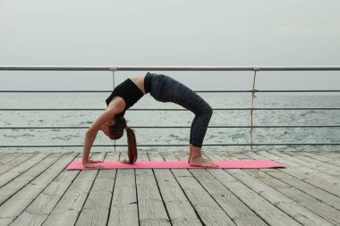 Yoga minderinde, tahta zeminde genç bir kadın.