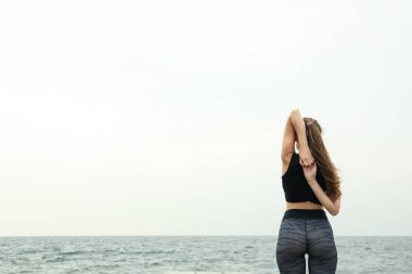 Deniz kenarında yoga yapan genç bir kadın, mesaj için yer var.