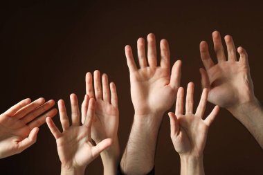 Erkek ve kadın elleri kahverengi arka planda, yakın plan.