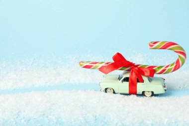Çatıda Noel şekeri ve kar olan bir araba.