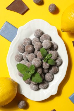 Sarı arka planda beyaz bir kasede çikolata topları.