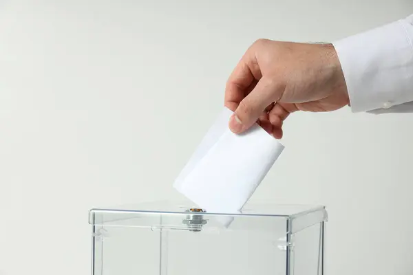 Voting box and form in male hand on white background