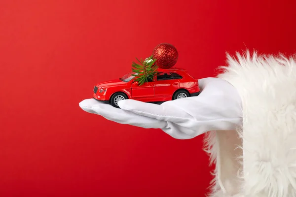 A car with New Year\'s decorations, in the hand, in the hands of Santa Claus.