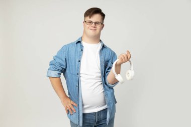 Elinde kulaklık olan Down sendromlu genç bir adam.