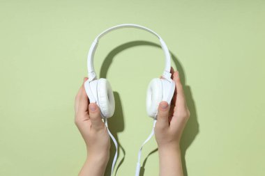Beyaz, kulaklıklı, yeşil arka planda dinleme cihazı olan..