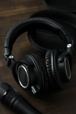 Siyah, büyük kulaklıklı, masada mikrofonlu..
