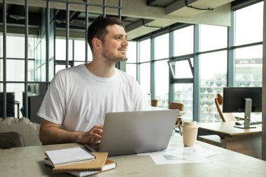 Dizüstü bilgisayarda çalışan çekici bir genç.