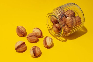 Sarı arka planda cam kavanozdaki fındıklı kurabiyeler