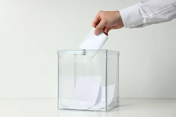 Voting box with papers and male hand on white background