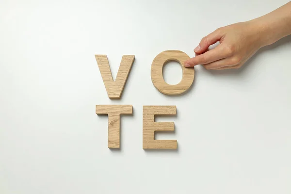 Word Vote from wooden letters and hand on white background, top view