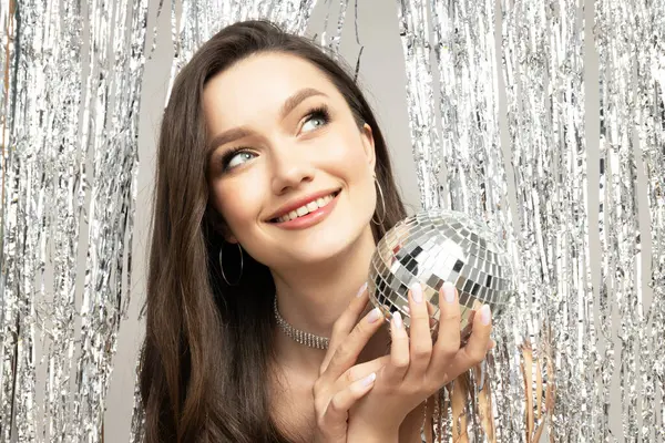 Attractive brunette at a party with a disco ball in her hand
