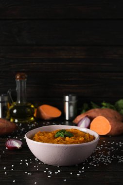 Tatlı patates püresi kasede ve ahşap arka planda malzemeler