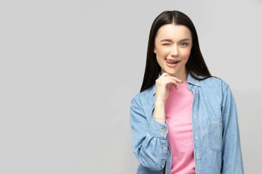 Gri arka planda poz veren çekici genç esmer.