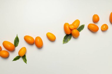 Kumkuat ve yapraklar beyaz arkaplanda, üst görünümde