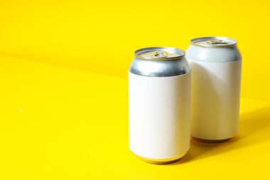 Sarı arka planda içecekler için teneke kutular.