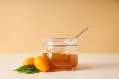 Bej arka planda kumkuat ve reçel kavanozu