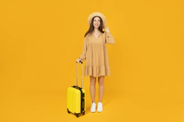 Sarı arka planda bavulu olan genç kız..