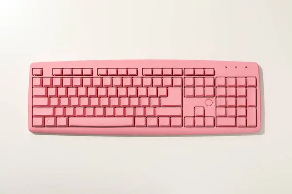 Pink computer keyboard on white background, top view