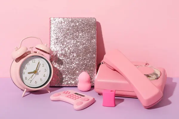 Phone, alarm clock, notepad and calculator on pink background
