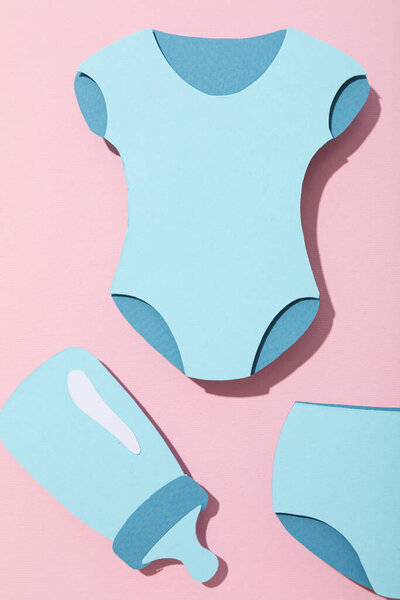 Paper baby things on pink background, top view