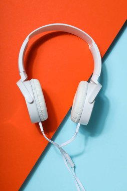 Beyaz, tam boy, mavi-turuncu arka planda kablolu kulaklık..