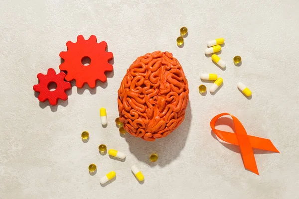 Orange human brain model with pills and gears