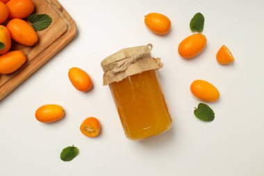 Kumkvat, mutfak tahtası ve reçel kavanozu beyaz arka planda, üst manzara