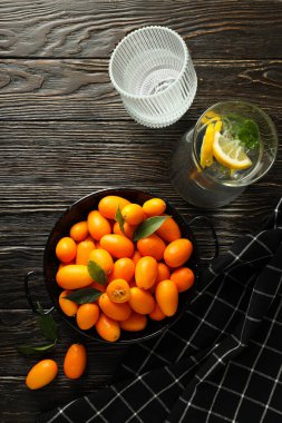 Kumkuat kasede, havlu ve bir bardak su koyu ahşap arka planda, üst manzara