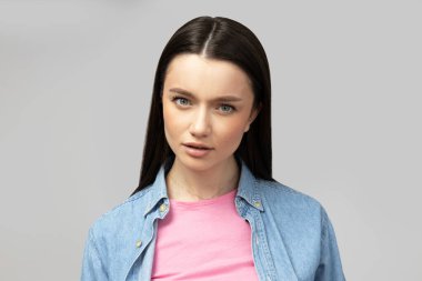 Gri arka planda poz veren çekici genç esmer.