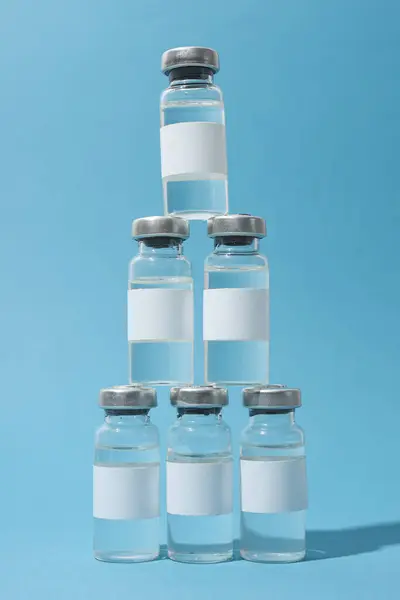 Glass medical bottles with vaccine on blue background