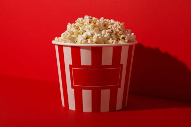 Kırmızı arka planda büyük bardakta patlamış mısır.