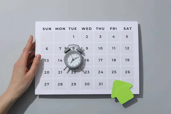A small alarm clock with a calendar