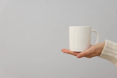 Bir kadın elinde beyaz bir bardak tutuyor.