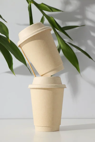Paper cups with lids and green leaves