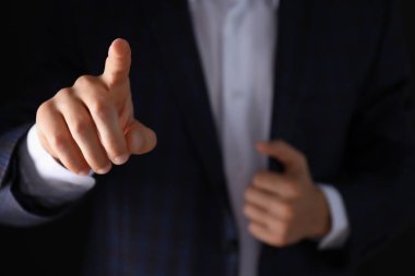 Takım elbiseli ve eli koyu arka planda olan adam, yaklaşın.